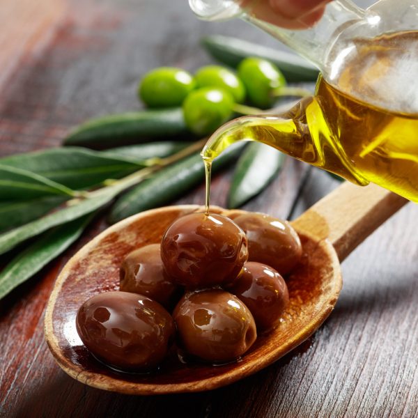 Olives in a wooden spoon and olive oil